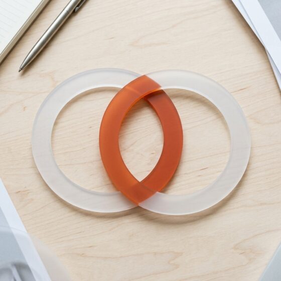 Twee overlappende matte ringen op een houten bureau, waarvan het overlappende deel oranje is