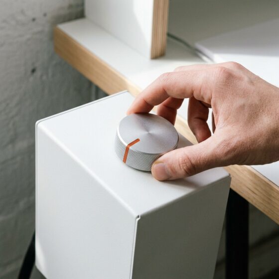 Hand draait aan een aluminium draaiknop met oranje streepje op een witte kast, als beeld voor bijsturen